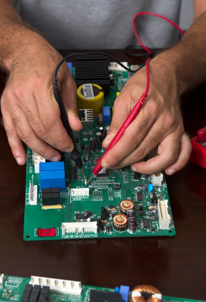 Services Close-up of hands using probes to test a circuit board during electronic repair.